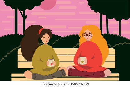 two girls sit in lotus in park drink tea 