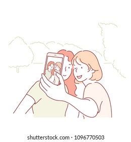 Dos chicas están tomando fotos al aire libre en sus teléfonos celulares. ilustraciones de diseño de doodles vectoriales de estilo dibujado a mano.