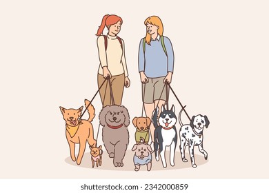 Two girls walk dogs on leashes in park and communicate enjoying spending time with animals. Women with dogs of different breeds love their own pets recommending to take puppy from shelter