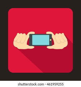 Two hands holding mobile phone icon in flat style with long shadow. Device symbol