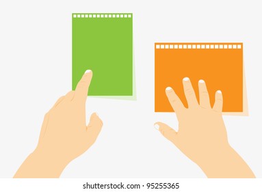 Two hands lie on student's writing-books of green and orange color