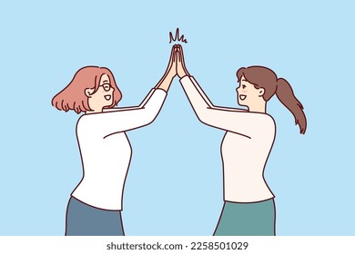 Two happy women rejoice high five greet each other after long-awaited meeting. Positive girls in casual clothes are happy to know about next vacation and joint summer trip