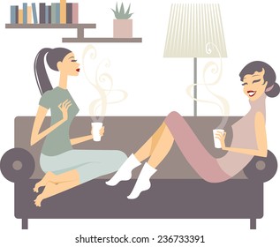 Two happy young female friends with coffee cups conversing in the living room at home