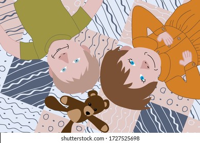two kids lying on a quilt with a teddy bear