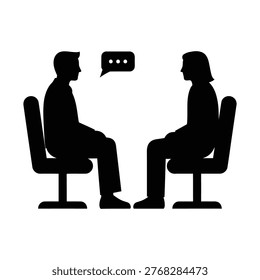 Two people sit facing each other in chairs, engaged in a conversation or interview.