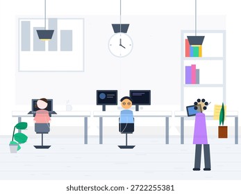 Dos personas trabajan en escritorios con computadoras en una oficina. Otra persona está tomando una foto de ellos. Algunas plantas y estantes están en el fondo.