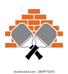 Two pickleball paddles crossed in front of orange brick wall background