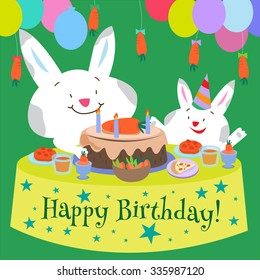 Two rabbits sitting next to a table with a birthday cake on it.