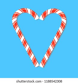 Two red striped candy cane laid out in form of heart on blue background