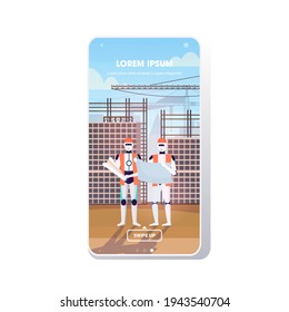two robots architects in uniform holding blueprints artificial intelligence technology architect concept construction site background smartphone screen mobile app full length copy space
