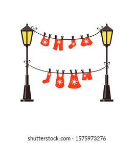 Two ropes of red christmas clothes hanging between two black and yellow street lights. Winter vector illustration. Park decoration. 