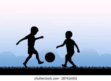 Two small boys kicking a ball on the grass