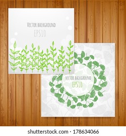 Two spring backgrounds with green leaves and plants on wooden texture. Vector illustration.