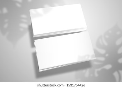 Two stacks of blank white business cards in perspective. Mockup for design or branding with realistic Monstera plant shadows 