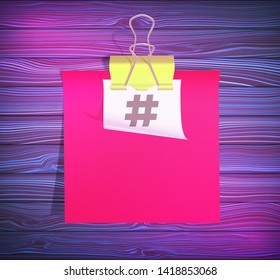 Two stickers linked by binder clip isolated on wooden background. Dark wood surface textured in the form of wooden boards. The symbol hashtag is printed on white sticker. Copy space illustration.