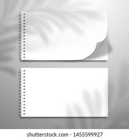 Two white blank spiral notebooks or albums. At one top sheet is bent. Flat lay mockup with palm tree sadow