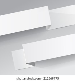 Two white diagonal sheets of paper on a grey background. Origami 