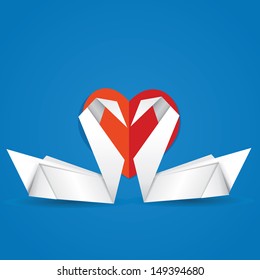 Two white paper swans and red heart on blue background.