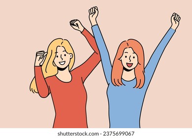 Two women friends triumphantly raise hands up celebrating long-awaited meeting or successful completion of college. Cheerful girl friends dancing at disco waving arms and enjoying cool music