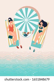 Two women are lying on sun loungers under an umbrella on the beach by the sea