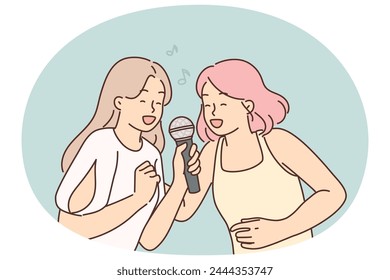 Two women sing song in karaoke at house party. I get positive emotions from musical leisure. Young cheerful girls with microphone enjoy singing in karaoke club or professional recording studio