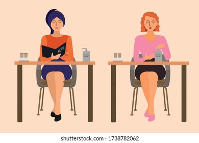 Two women sit at a table in a cafe. The woman studies the menu. A woman wipes her hands with antiseptic.