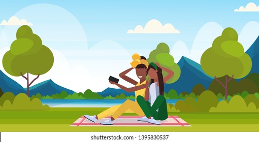 Two Women Taking Selfie Photo On Smartphone Camera African American Female Characters Sitting Outdoor On Grass Posing Over Nature Landscape Mountains Background Flat Full Length Horizontal