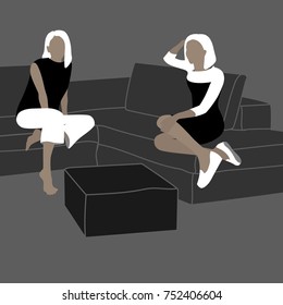 Two young blonde woman relaxing chatting on a modern gray sofa