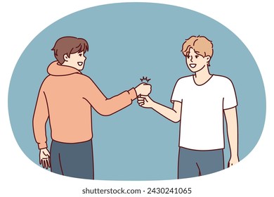 Two young guys bump their fists when they meet, making greeting to members of student fraternity. Positive teenage boys in casual clothes say goodbye after fun together walk