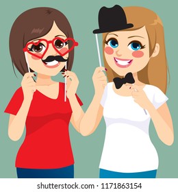Two young teenager girls friends playing with funny pose and photo booth masks party