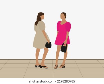 Two young women in cocktail dresses and with handbags stand together indoors