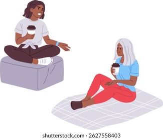 Two young women are sitting comfortably, holding disposable coffee cups and enjoying a relaxing break together, possibly discussing something interesting