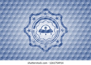 ufo with aline inside icon inside blue badge with geometric pattern.