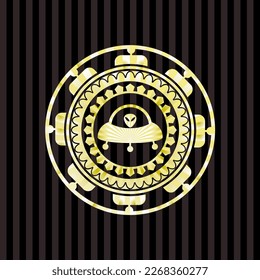 ufo with aline inside icon inside gold emblem or badge. 