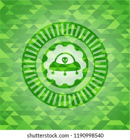 ufo with aline inside icon inside green emblem with triangle mosaic background