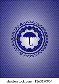 umbrella icon inside badge with denim background