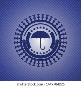 umbrella icon inside badge with denim texture