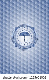 umbrella icon inside blue emblem or badge with abstract geometric pattern background.