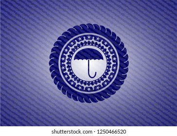 umbrella icon inside emblem with denim texture