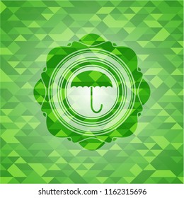 umbrella icon inside green emblem with mosaic background