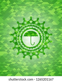 umbrella icon inside green emblem with triangle mosaic background