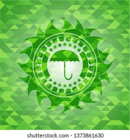 umbrella icon inside green emblem with mosaic ecological style background