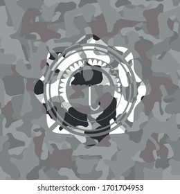 umbrella icon inside grey camouflaged emblem