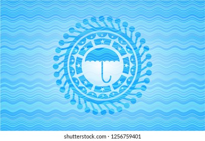 umbrella icon inside light blue water emblem background.