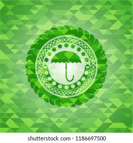 umbrella icon inside realistic green emblem. Mosaic background