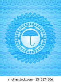 umbrella icon inside water wave emblem.