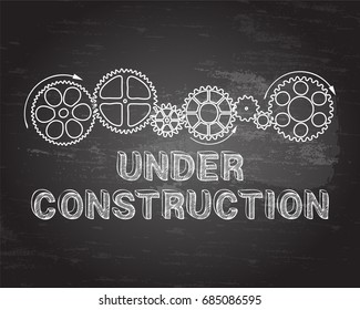 Under construction text with gear wheels hand drawn on blackboard background