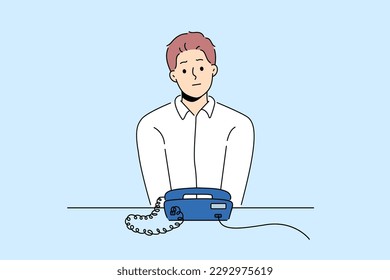 Unhappy man sit at desk look at landline phone waiting for someone call. Frustrated guy awaiting ring looking at corded telephone. Vector illustration. 