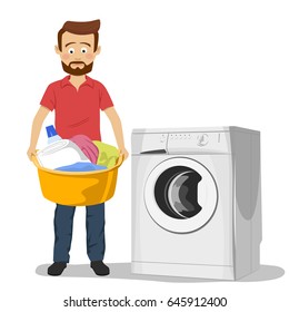 Unhappy young man standing next to washing machine with basin filled with dirty clothes