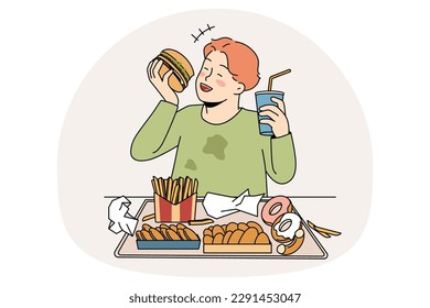 Unhealthy eating in childhood concept. Smiling cheerful fatty boy sitting and eating hamburger donuts french fries drinking lemonade enjoying junk food vector illustration